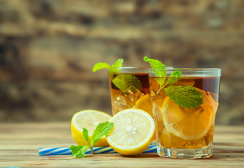 Iced tea with lemon slices and mint on wood background