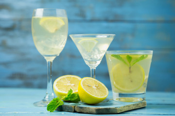 Lemonade or mojito cocktail with lemon and mint on wood background