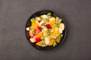Fruit salad bowl on grey stone background, top view. Diet food concept