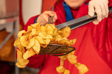 Crispy fried potato chips removed from the deep fryer, food street, market 