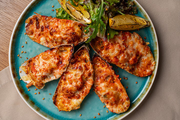 delicious cooked mussels with sauce, lemon and garlic bread and butter on a black plate on the dark wooden background, side view, horizontal