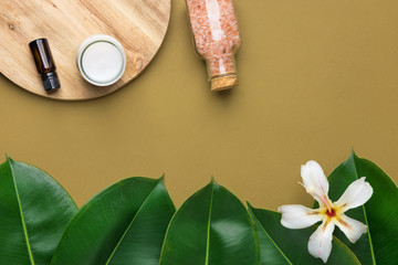 Amber glass with essential oil homemade coconut cream pink Himalayan salt green plants white flower on earthy brown background copy space. Self care body face skin beauty concept home spa wellness