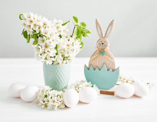 Easter bunny and White Easter eggs and spring branch with flowers on wooden background. Spring easter greeting card.Flowers Cherry flowering.Spring flowers. Beautiful Orchard.Springtime