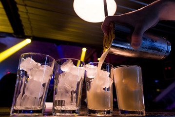 Bright cocktails - shots at the bar. Colorful footage in a nightclub. Alcoholic drink of different colors. Nightlife scene. Shots at the bar table. Several glasses of alcohol 