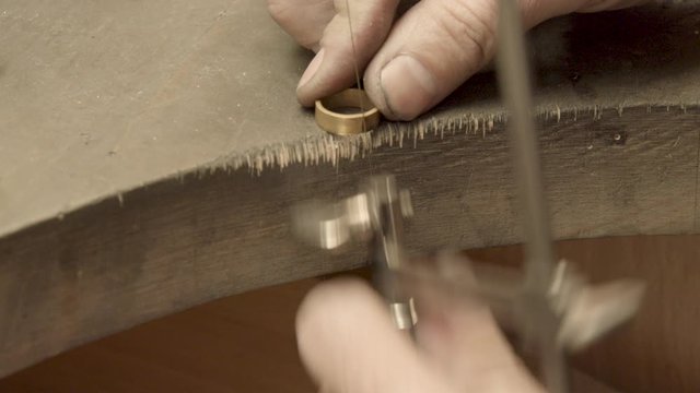 Close-up of a goldsmith sawing a piece of a ring for resizing