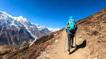 A man trekking on the Annapurna Circuit Trek, Himalayas, Nepal. Panoramic view on snow caped Annapurna chain. Lots of dried grass. High altitude, massive mountains. Freedom and adventure