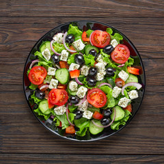 Greek salad. Tasty greek salad on a black plate. Top view