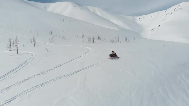 Men riding on snowmobile on snowy fields and highlands at winter day. Tourist driving on snowmobile at winter vacation on snowy highlands landscape.