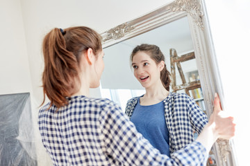 Woman setting up apartment hangs mirror