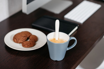A minimal desk with a computer a couple of coffee and biscuits. Modern workspace