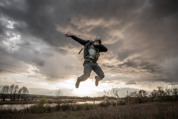 The guy makes a dab during the jump on a beautiful sunset background in field. Concept of modern culture.