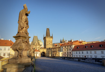 Fototapeta na wymiar Famous Charles Bridge in Prague. Statue of St. Adalbert (Vojtech in Czech) pointing towards Lesser Town and Castle. No people on the bridge due to Covid-19 outbreak in April 2020