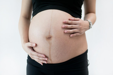 Closeup of a pregnant woman holding her tummy.