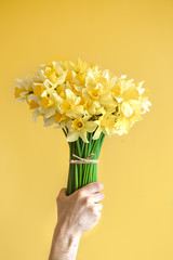 Background male hands with a bouquet of flowers .