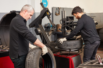 Zwei Mechatroniker in der Autowerkstatt mit Reifen