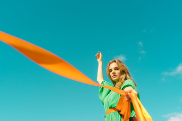 Portrait of young woman wearing a green dress holding orange ribbons