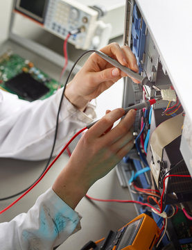 Female technichian working on open computer, using measuring device, close up