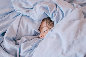 Portrait of sleeping girl lying under blanket