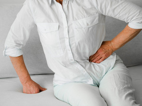 Old patient with pain sitting on couch - Powered by Adobe