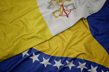 waving colorful flag of bosnia and herzegovina and national flag of vatican city.