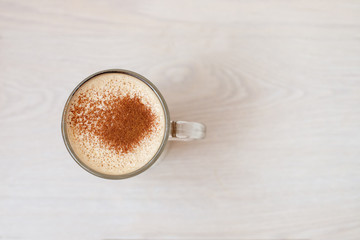 glass Cup of coffee cappuccino with foam and cinnamon top view on a wooden background