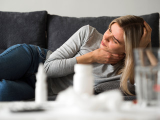 Sore throat. Woman with neck pain on couch.