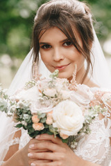 Naklejka premium portrait of a bride with flowers in a beautiful full-length wedding dress, young brunette, tender photo wedding portrait