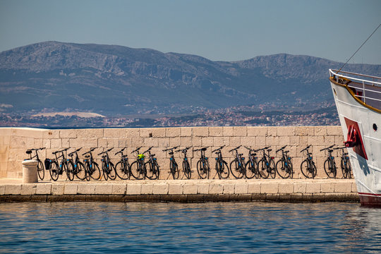 Port and pier of village Postira on island Brac in Croatia with tourist boat and cycles