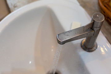 Silver faucet in bathroom,flow of water from faucet.