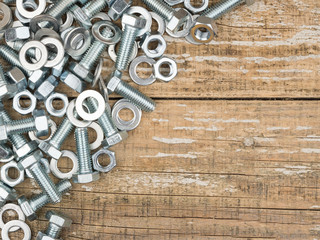 Bolts and nuts on wooden background. The view from the top.