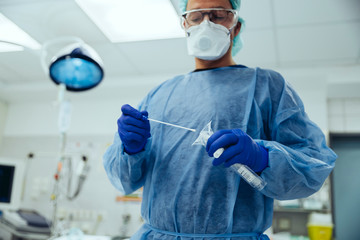 Emergeny doctor putting a swab into a tube in hospital
