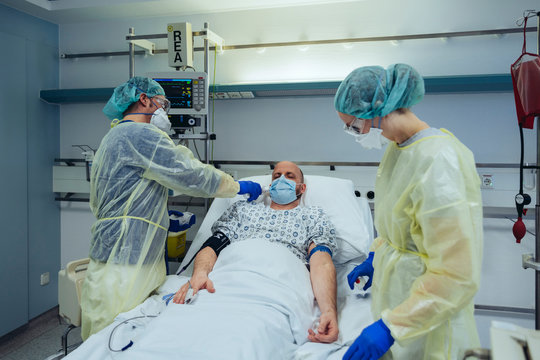 Doctors caring for patient in emergency care unit of a hospital taking temperature