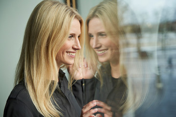 Portrait of happy blond woman looking out of window