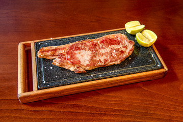 Entrecote served on stone plate and bamboo on wooden table