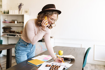Image of cheerful woman talking on cellphone while studying