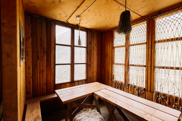 The interior of the fishing house. Wooden tables, fishing nets. Big table. Old cafe