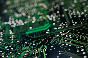 A macro detailed image of a small green microchip circuit board.