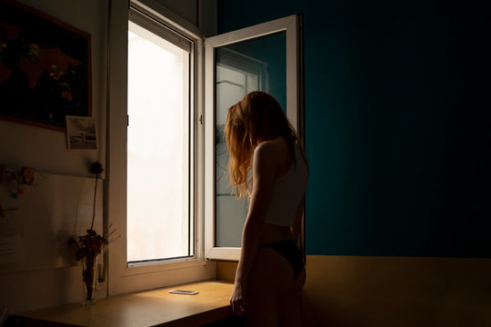 Young woman standing at the window at home