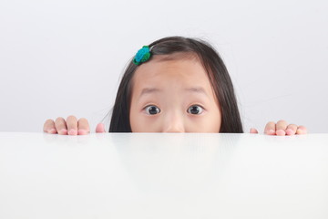 Portrait of little boy looking at the camera from under the table isolated on white background.