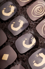 Mixed luxury dark and milk chocolate truffles. Assorted delicious handmade chocolate pralines in a row. Dark brown with golden ornaments. Studio shot