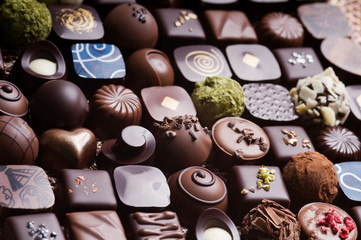 Mixed luxury dark and milk chocolate truffles. Assorted delicious handmade chocolate pralines in a row. Full frame background. Studio shot. Close-up