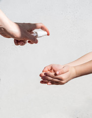 Hand treatment with a sanitizer. Sanitizer in a bottle in the hands of an adult sprays on the substituted palms of the child on white background. copy space
