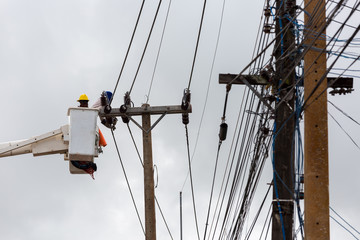 electricians repairing wire of the power line on electric power pole