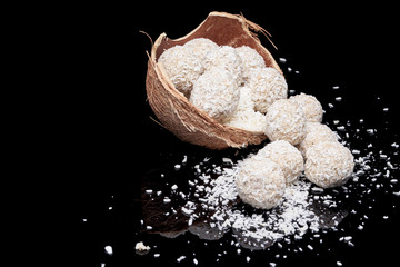 White coconut balls, raw and healthy sugar free rafaello candies on black glass background....