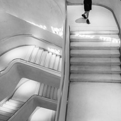 Una persona bajando por una escalera blanca con pasamanos de metal