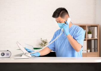 Asian male receptionist working at desk in clinic
