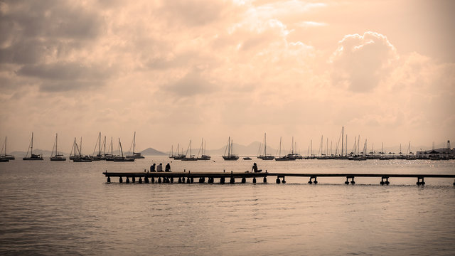 Atardecer en la costa de Cartagena con los barcos atracados y un muelle con personas sentadas