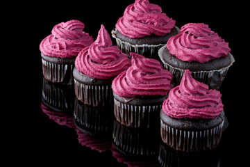 Vegan chocolate and blackcurrant cupcakes. Dark muffins with cashew nuts and black currant cream on top.
