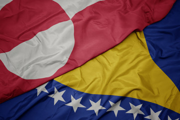 waving colorful flag of bosnia and herzegovina and national flag of greenland.