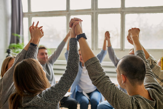 young caucasian people celebrating recovery from alcohol addiction, team work of anonymous addicts club, raised hands up together